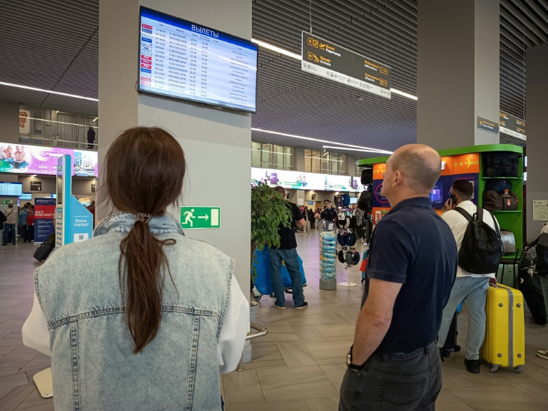 Des passagers regardent un panneau d'affichage des vols à l'aéroport de Kaliningrad, en Russie, le 4 juillet 2026
